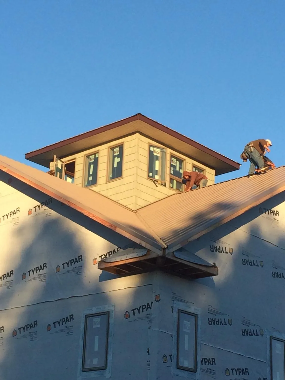 Roofers working around a rooftop cupola on a new metal roof at sunset — Roof Waterproofing in Trimble by Roofing Brothers